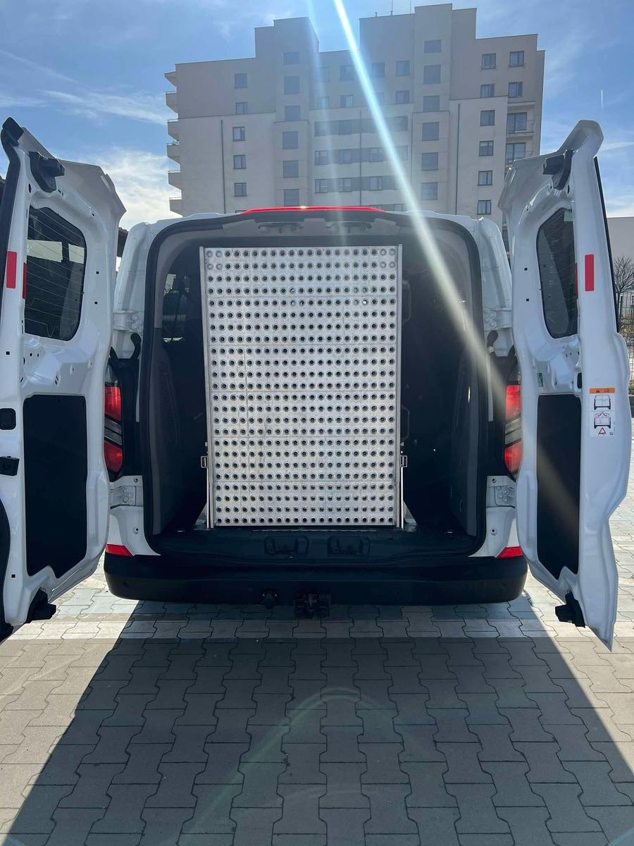 2.	Ford  TRANSIT Custom, z otwartymi drzwiami z tyłu. Widok przedstawia złożoną platformą do transportu os&oacute;b na w&oacute;zkach inwalidzkich. 