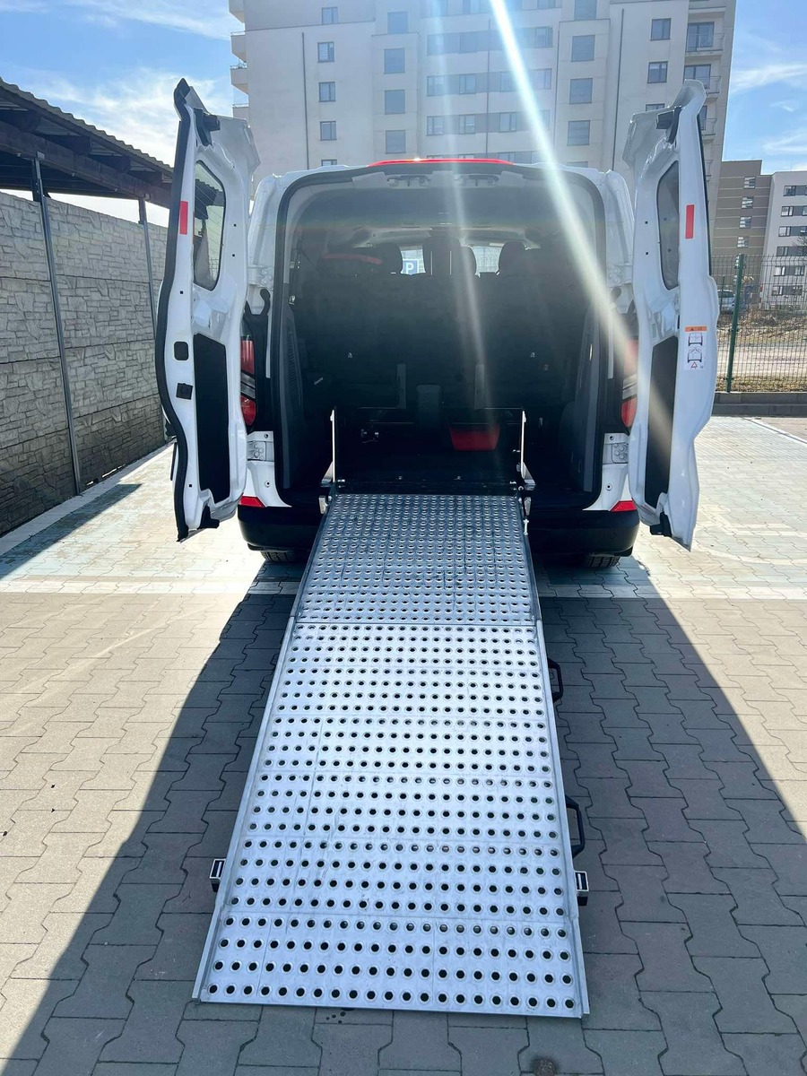 1.	Ford  TRANSIT Custom, z otwartymi drzwiami z tyłu. Widok przedstawia rozłożoną platformę do transportu os&oacute;b na w&oacute;zkach inwalidzkich