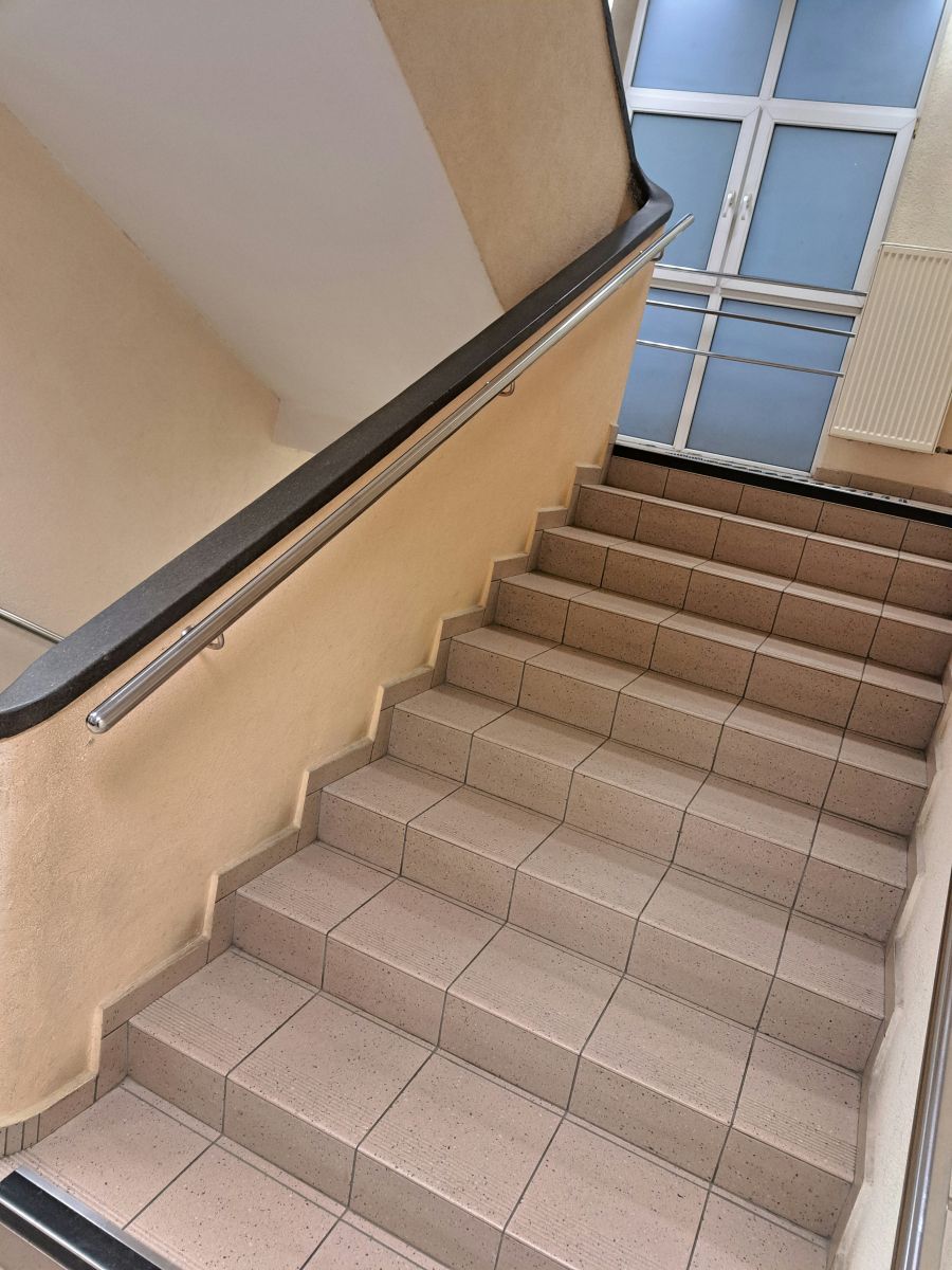 Wejście do budynku Urzędu Miasta Rzeszowa  przy ul.  Kopernika 15 z  poręczami zamontowanymi wzdłuż schod&oacute;w, zapewniającymi bezpieczeństwo poruszania się  po schodach.